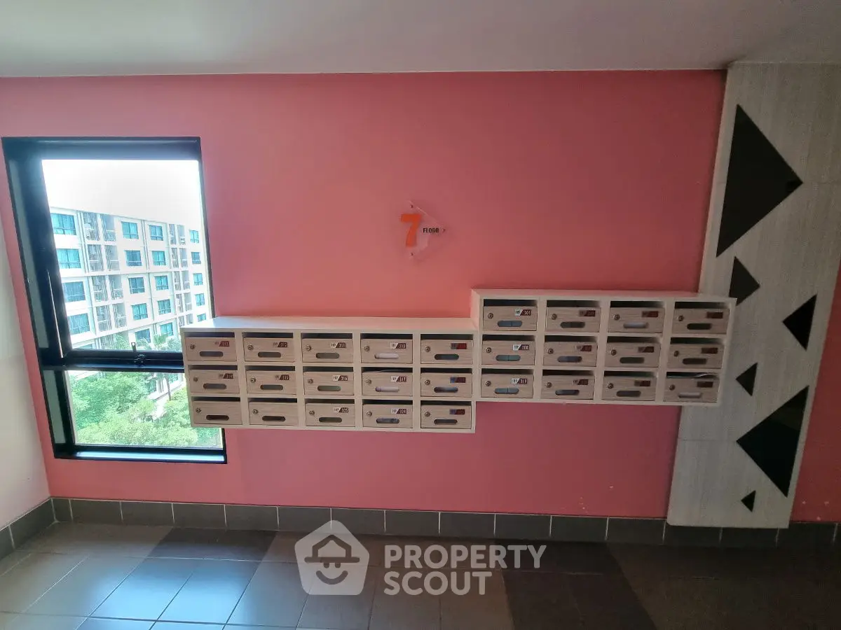 Modern apartment building hallway with mailboxes and window view.