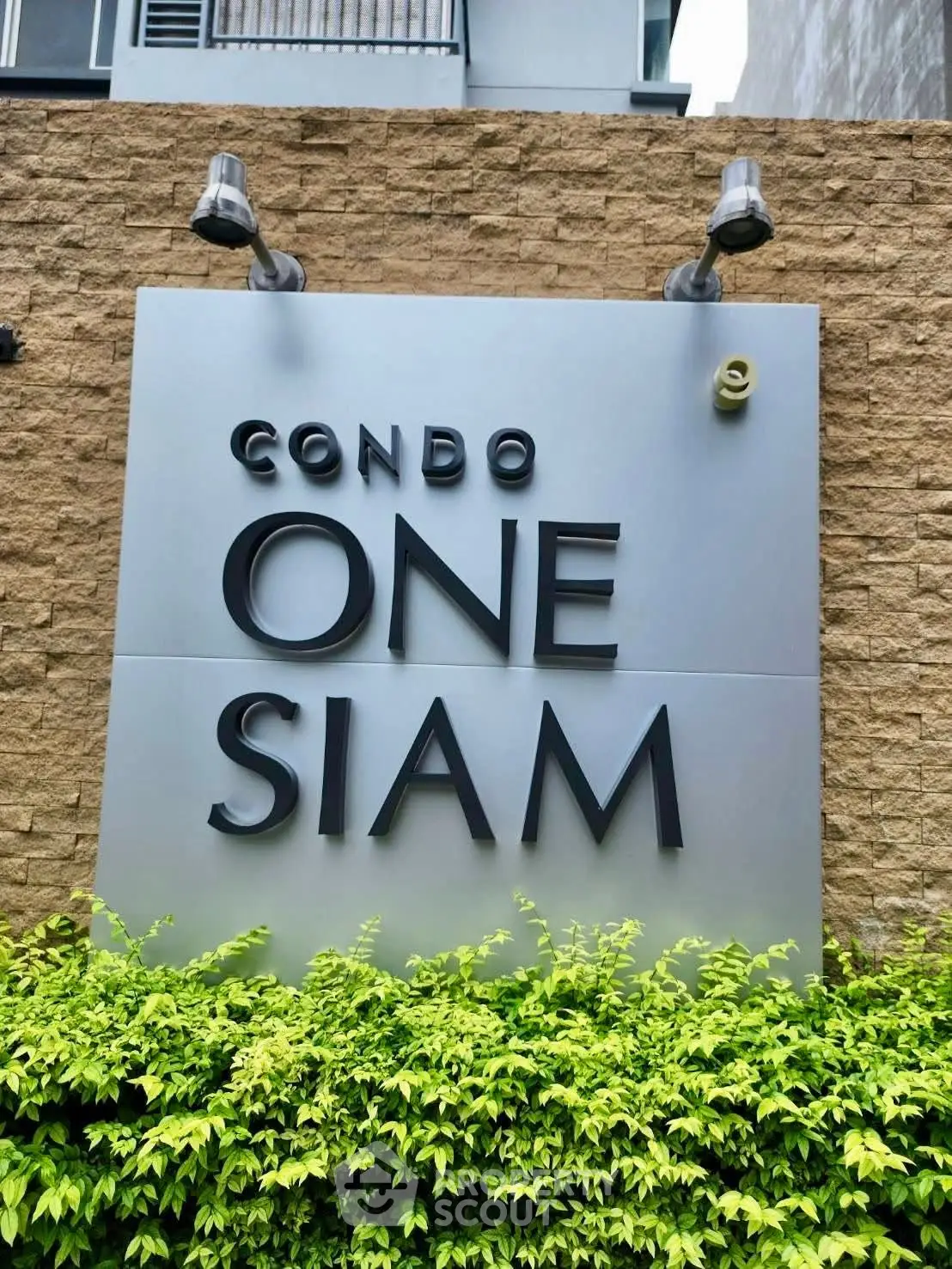 Modern condo sign with lush greenery at One Siam, showcasing urban living.