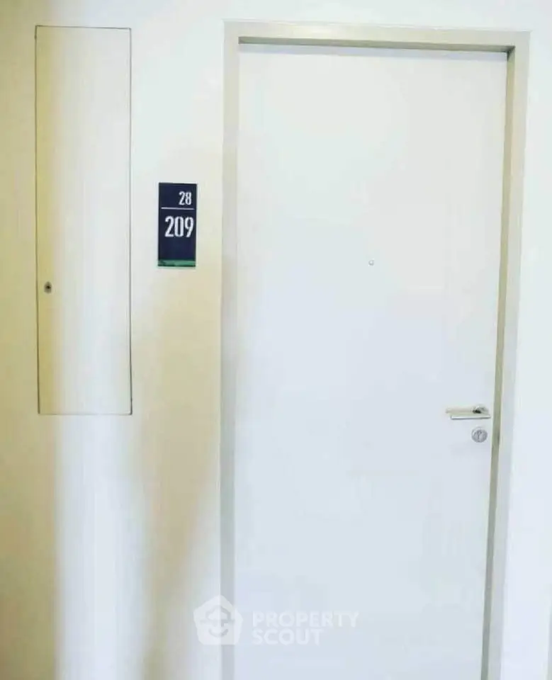 Modern apartment entrance with sleek white door and room number 209, showcasing minimalist design.
