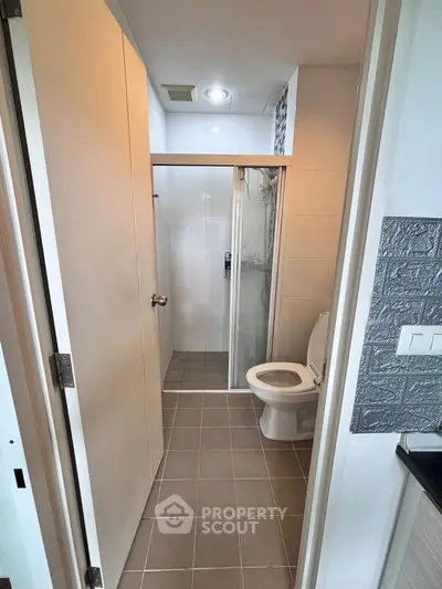 Compact modern bathroom with shower and toilet in sleek design.