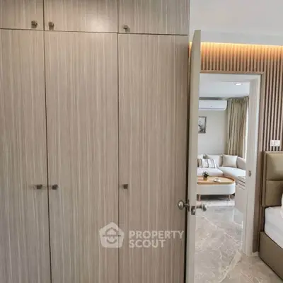 Modern interior with stylish wooden wardrobe and glimpse of cozy living room.