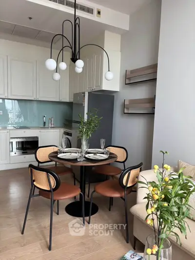 Modern kitchen with dining area, stylish lighting, and sleek appliances in a contemporary apartment.