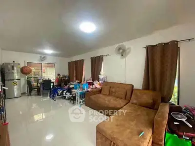 Spacious living room with brown sofa and dining area, featuring modern appliances and ample natural light.