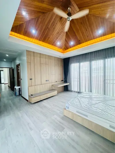 Spacious modern bedroom with wooden ceiling and large windows