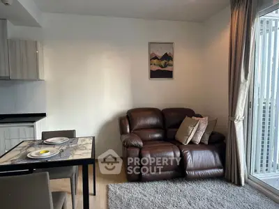 Modern living room with leather sofa and dining area, featuring a cozy atmosphere and natural light.