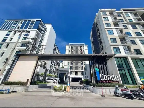 Modern condominium entrance with sleek design and urban appeal under clear blue sky.