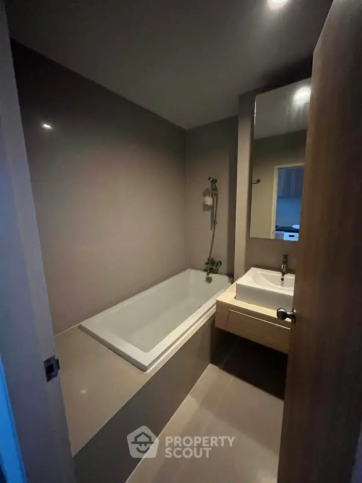 Modern bathroom with sleek bathtub and stylish sink in a cozy apartment.