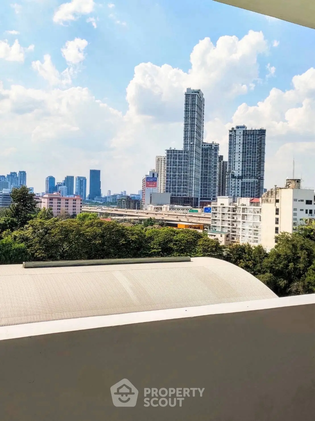Stunning cityscape view from a modern balcony overlooking skyscrapers and lush greenery.