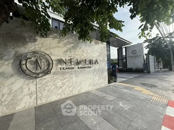 Modern entrance of New Era Ekamai-Ramintra with stylish marble facade.