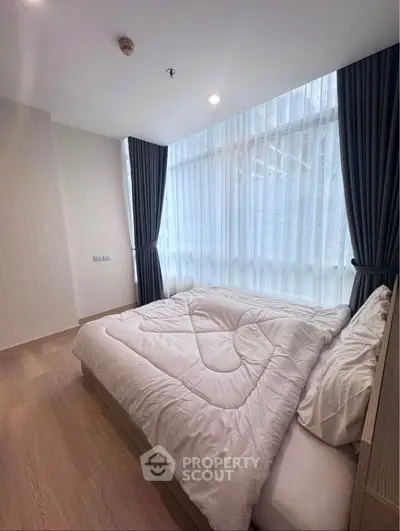 Modern bedroom with large windows and elegant curtains in a stylish apartment.