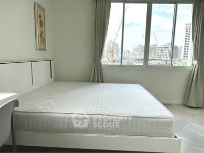 Spacious bedroom with city view and natural light in modern apartment.