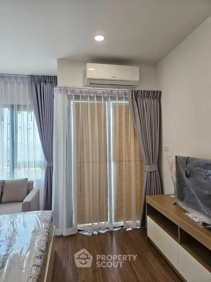 Modern living room with air conditioning and elegant curtains, featuring a cozy sofa and stylish TV stand.