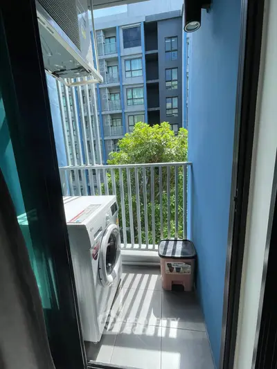 Compact balcony with washing machine and city view, perfect for urban living.