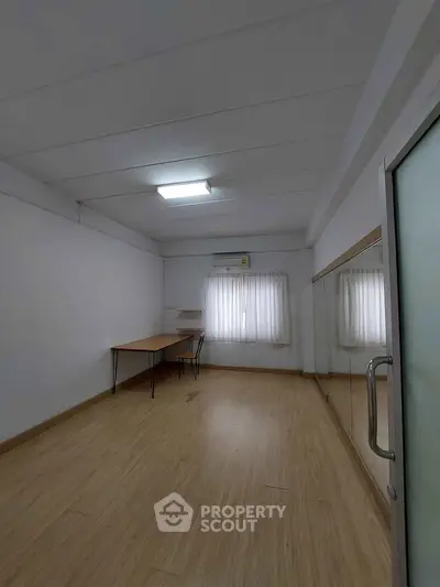 Spacious study room with wooden flooring and ample natural light.