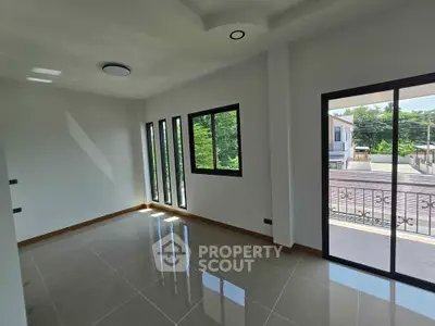 Spacious sunlit room with large windows and balcony access in modern home