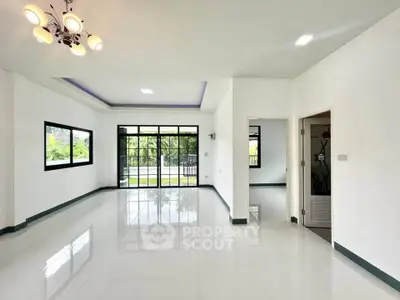 Spacious modern living room with large windows and elegant lighting, perfect for natural light and comfort.