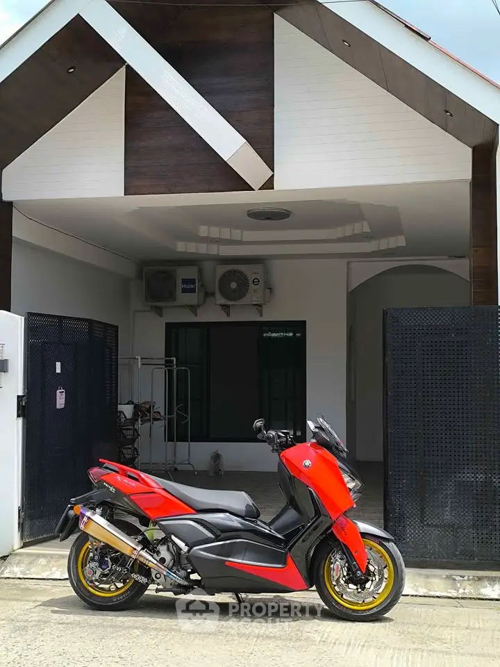 Modern house exterior with stylish architecture and a vibrant red motorcycle parked in front.