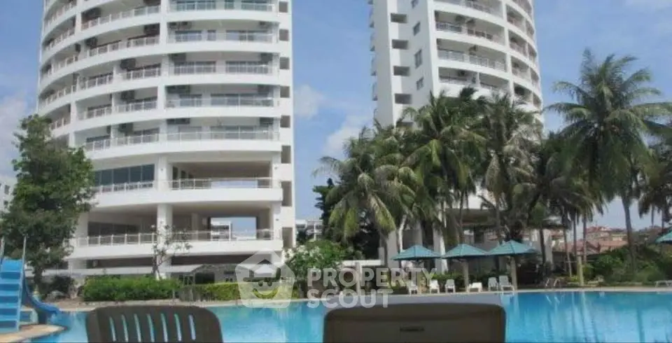 Luxurious high-rise apartment with stunning poolside view and lush palm trees.