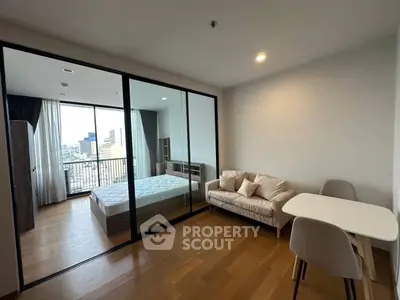 Modern apartment with bedroom and living area, featuring a city view balcony.