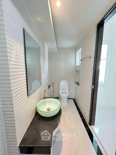 Modern bathroom with sleek design, featuring a round glass sink and contemporary fixtures.