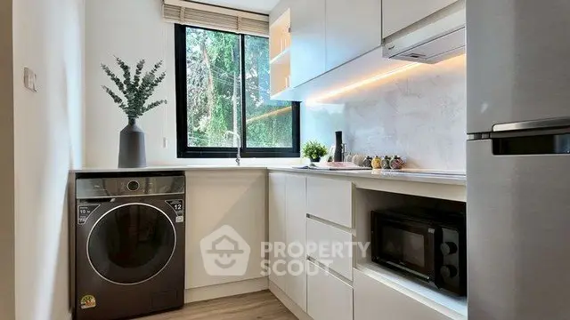 Modern kitchen with sleek appliances and large window offering natural light.