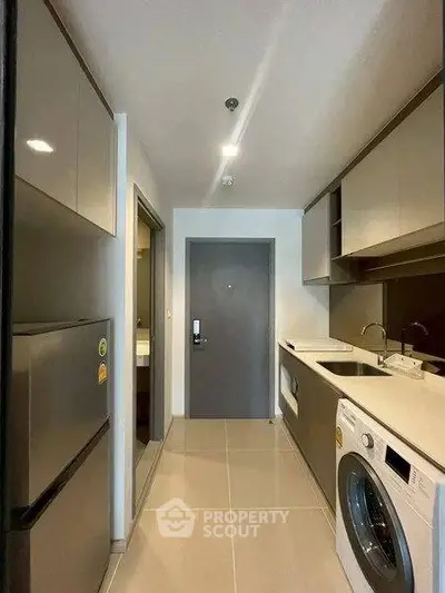 Modern kitchen with sleek cabinetry, washing machine, and fridge in a compact layout.