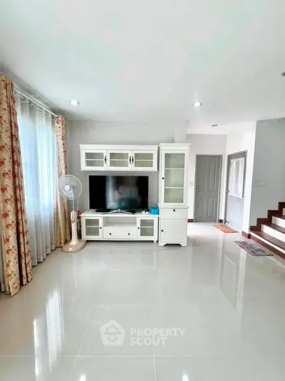 Spacious living room with modern entertainment center and elegant curtains