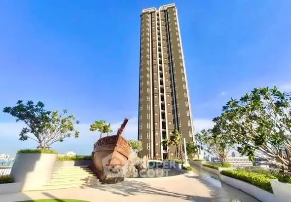 Stunning high-rise building with unique ship sculpture and lush landscaping under a clear blue sky.
