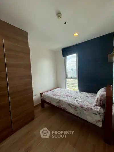 Cozy bedroom with single bed and city view, perfect for urban living.