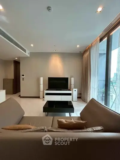 Modern living room with sleek furniture and city view through large windows.
