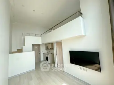 Modern loft apartment with high ceilings and sleek interior design, featuring a washing machine and wall-mounted TV.