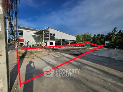 Spacious vacant lot with potential for development, featuring clear skies and surrounding greenery.