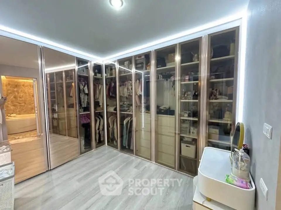 Luxurious walk-in closet with glass doors and elegant lighting