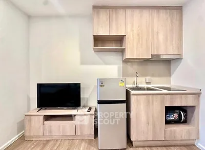 Modern compact kitchen with integrated appliances and sleek wooden cabinetry in a cozy apartment.