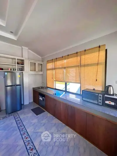 Spacious kitchen with modern appliances and large window for natural light.