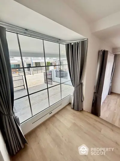 Spacious corner unit with large windows and elegant curtains offering ample natural light.