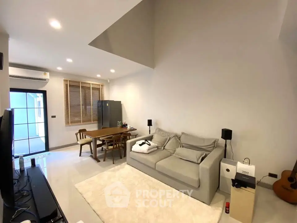 Modern living room with cozy gray sofa and dining area, featuring stylish decor and natural light.