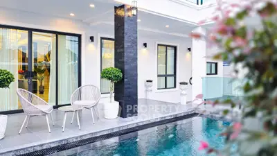 Luxurious modern home with elegant poolside patio and stylish outdoor seating.