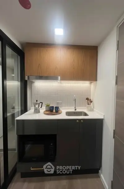 Modern compact kitchen with sleek cabinetry and built-in microwave