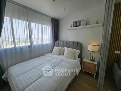 Cozy bedroom with large window and stylish decor, perfect for relaxation.