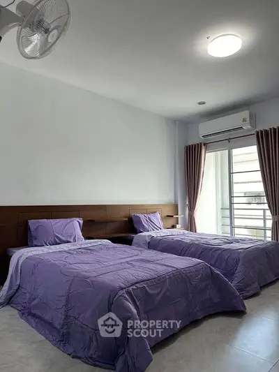 Spacious bedroom with twin beds and modern decor, featuring natural light and air conditioning.