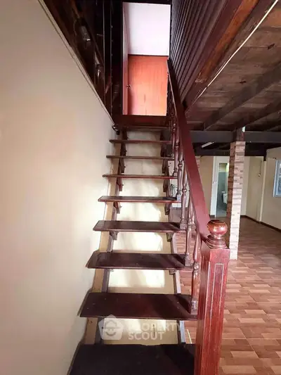 Charming wooden staircase leading to upper level in rustic home interior.