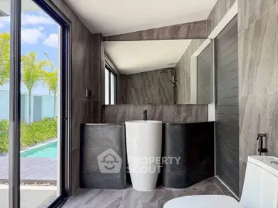 Luxurious modern bathroom with sleek design and poolside view, featuring elegant fixtures and large mirror.