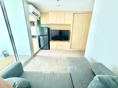 Modern living room with sleek furniture and built-in storage, featuring a large TV and air conditioning.