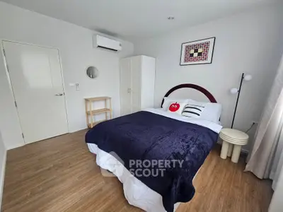 Cozy bedroom with modern decor and wooden flooring, featuring a comfortable bed and stylish furnishings.
