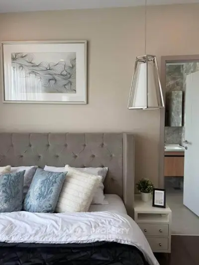 Elegant bedroom with plush headboard and modern decor, featuring stylish pendant lighting and framed artwork.