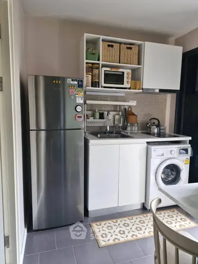 Compact kitchen with modern appliances including fridge, microwave, and washing machine.