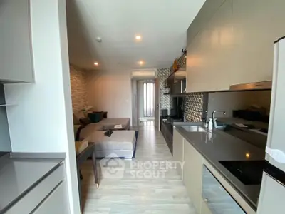 Modern open-layout kitchen with sleek cabinetry and cozy living area in contemporary apartment.