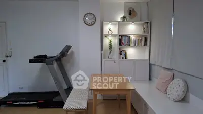 Cozy home gym with treadmill and stylish bookshelf in modern living space.