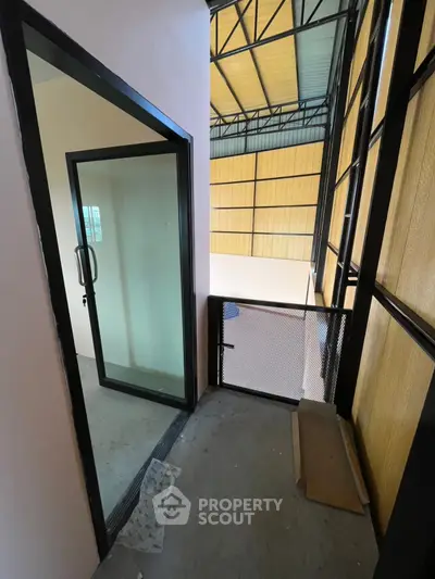 Modern industrial-style balcony with glass door and metal railing